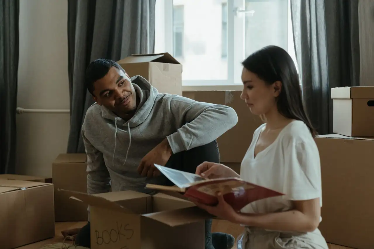 A couple exploring their new home while unpacking boxes and looking at a photo album.
